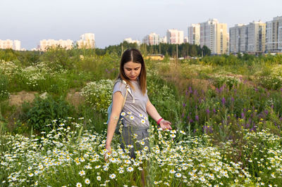 Full length of smiling woman standing against plants