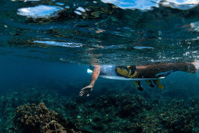 Underwater view of a hand surfer on a surfboard in a clear sea
