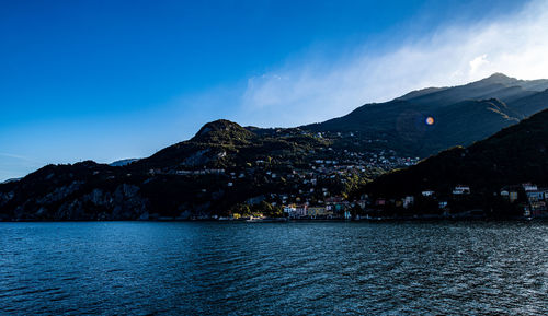 Scenic view of sea and mountains against blue sky