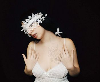 Portrait of woman standing against black background