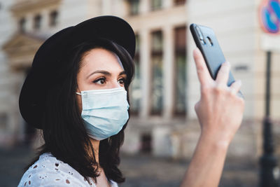 Close-up of young woman holding smart phone standing outdoors