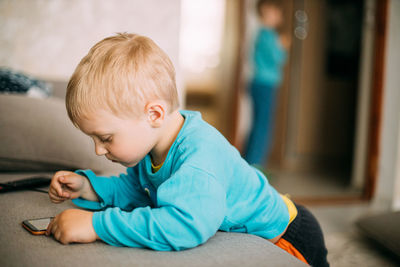 Cute boy sitting on floor at home