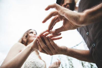 Low angle view of young couple holding engagement rings