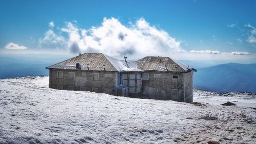 Built structure on snowcapped mountain against sky