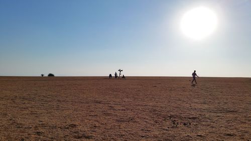 People on desert against sky during sunny day