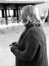 Side view of woman standing on footpath in city