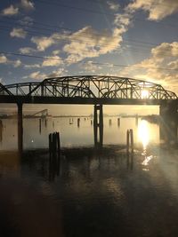 Silhouette bridge over lake against sky during sunset