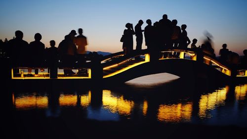 Silhouette of people standing on riverbank