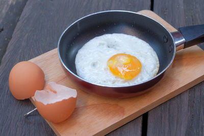 High angle view of egg in cooking pan on cutting board