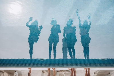 Reflection of people standing by swimming pool