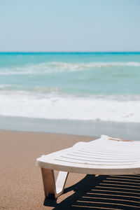 Deck chairs on beach against sky