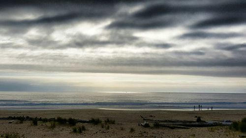 Scenic view of beach against cloudy sky