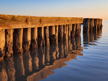 Wooden posts on beach against clear sky