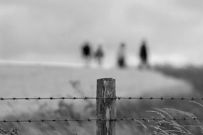 Barbed wire fence on land against sky