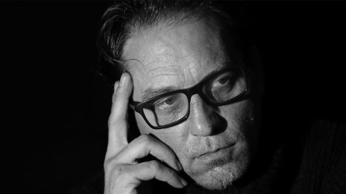 Close-up portrait of mid adult man against black background