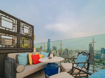 Chairs and tables on balcony against sky