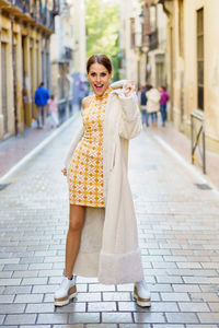 Portrait of young woman walking on footpath in city