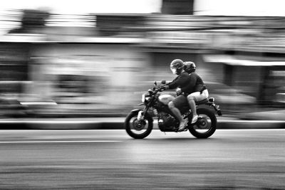 Blurred motion of man riding motorcycle on street