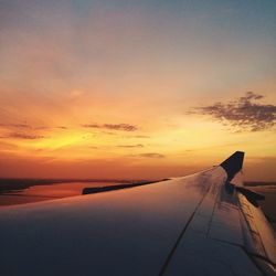 Airplane wing against sky during sunset