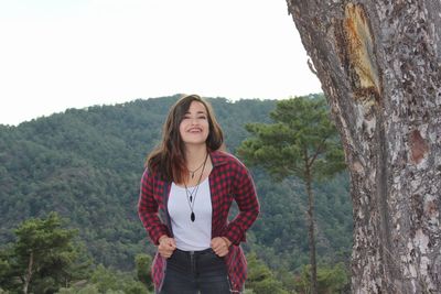 Young woman standing on mountain against clear sky