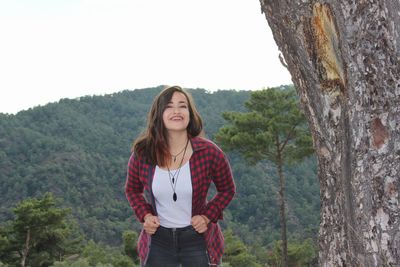 Portrait of smiling woman standing against mountains