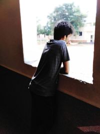 Rear view of boy looking through window