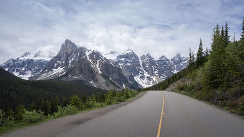 Road amidst trees and mountains against sky