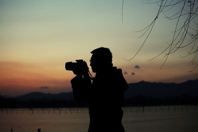 Man photographing through camera against sky