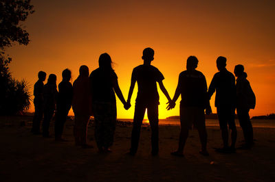 Silhouette people on beach against sky during sunset