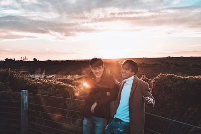 Young couple kissing against sky during sunset