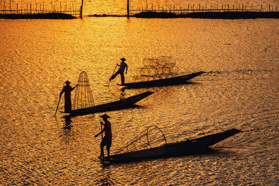 Silhouette people in boat on sea during sunset