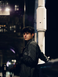 Portrait of young man standing in city at night