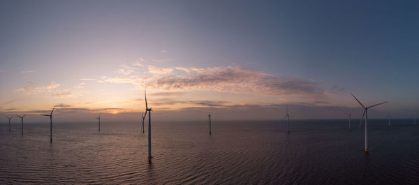 Wind turbines in sea against sky during sunset, windmill turbines in the netherlands 