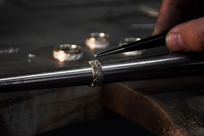 Close-up of hand of a goldsmith setting the diamond on the ring. craft jewelery 