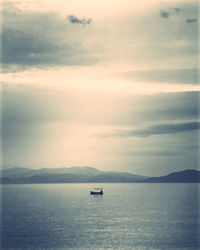 Boat sailing in sea against sky during sunset