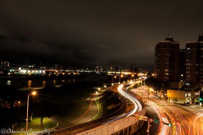 High angle view of illuminated street amidst buildings in city at night