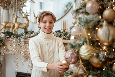 Boy decorates christmas tree at home