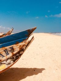 Fishing boat on beach against blue sky