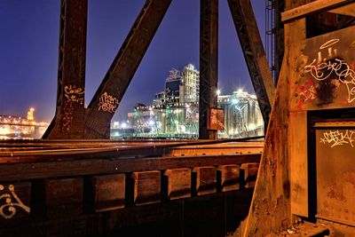 Bridge over illuminated buildings against sky at night