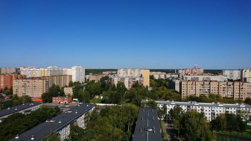 Buildings in city against clear blue sky