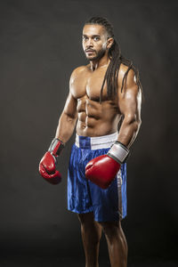 Portrait of shirtless boxer standing against black background
