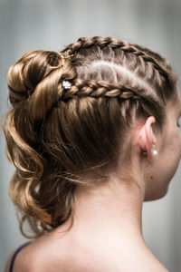 Close-up of woman with braided hair against gray background