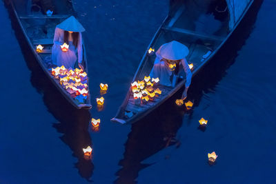 High angle view of women floating lighting equipment on lake at night