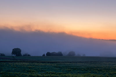 Scenic view of field against sky during foggy sunrise