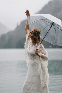 A tender sensual young woman bride in a fashionable wedding dress is standing in the rain in nature