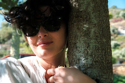 Portrait of a smiling young woman with tree trunk