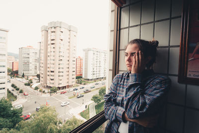 Portrait of young woman standing against buildings