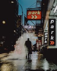 Rear view of people walking on wet road in city