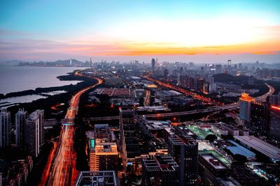 High angle view of city lit up at sunset