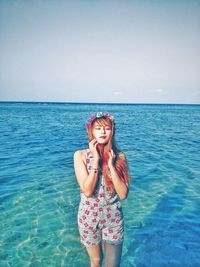 Beautiful woman wearing tiara with eyes closed standing in sea against sky